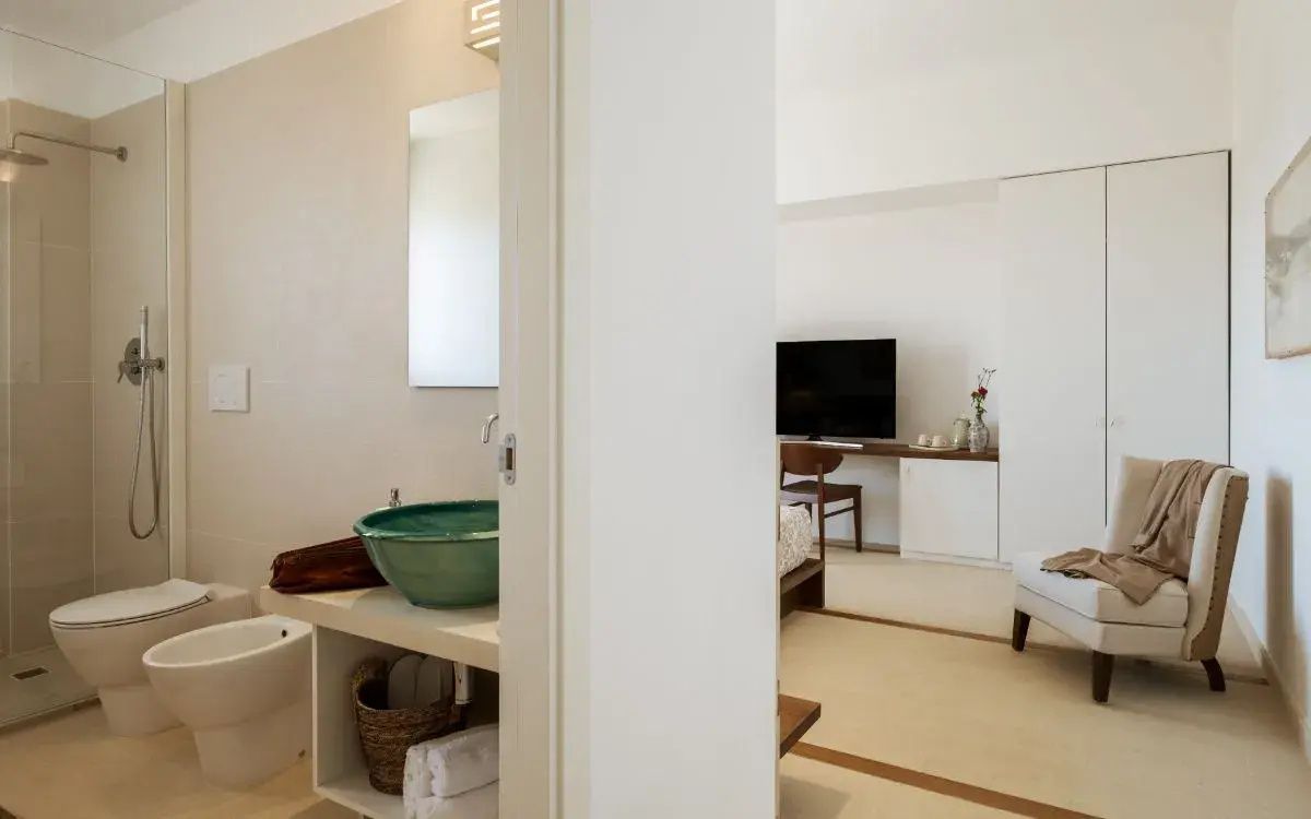 Badezimmerbereich mit grünem Waschbecken und Blick in das angrenzende Schlafzimmer.