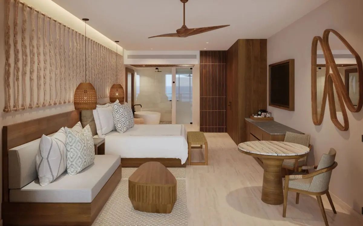 Modern eingerichtetes Hotelzimmer mit großem Doppelbett, Sitzecke und Holzmöbeln.