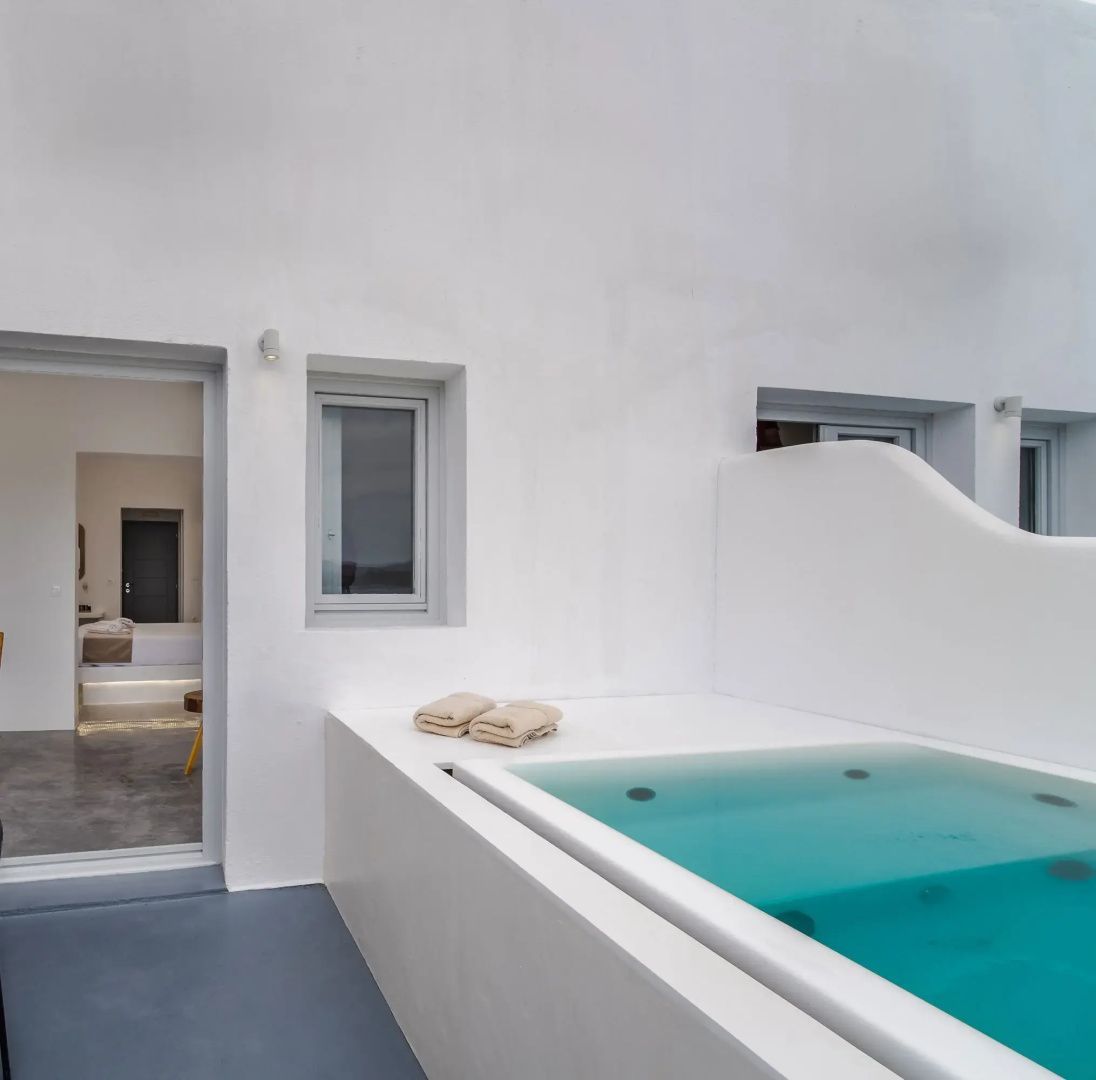 Außenbereich einer Suite mit privatem Jacuzzi, weißen Wänden und Blick ins Zimmer.