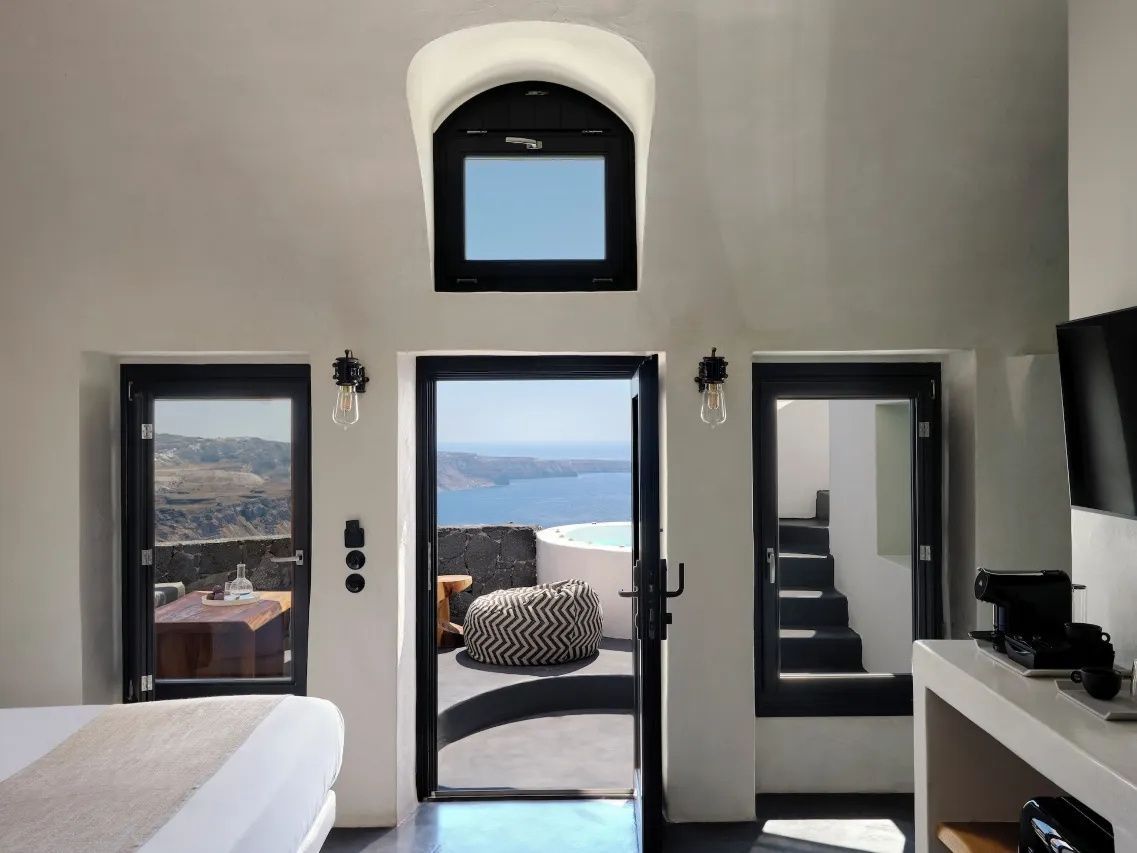 Blick aus dem Zimmer auf eine Terrasse mit Whirlpool und Weitblick ueber das Meer.