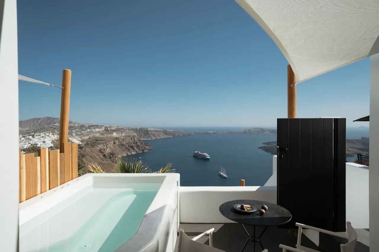 Terrassenausblick mit Whirlpool und Sitzbereich auf die Ägäis und die Vulkanfelsen von Santorin.