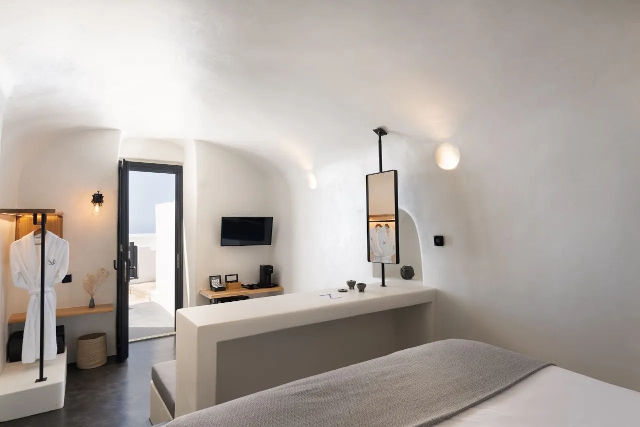 Weißes Höhlenzimmer mit Raumteiler, Fernseher und Blick zur Balkontür.