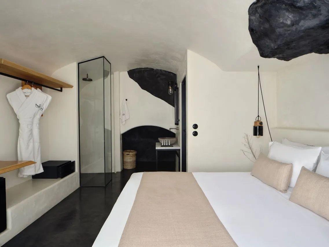 Hotelzimmer mit Bett, offenem Duschbereich aus Glas und Waschtisch.