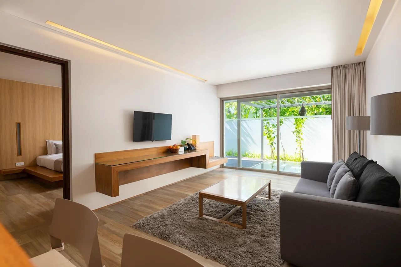 Wohnbereich einer Suite mit grauem Sofa, Teppich, Couchtisch und Blick auf die Terrasse.