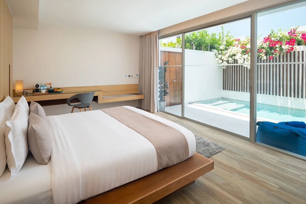 Modernes Hotelzimmer mit Doppelbett, Schreibtisch und Blick auf den privaten Pool.