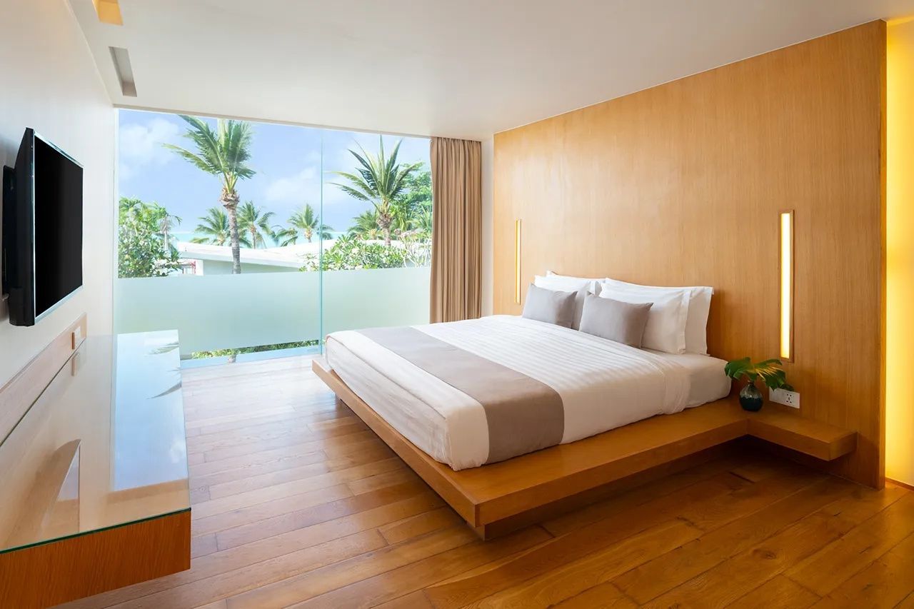 Modernes Schlafzimmer mit Holzfußboden, großem Doppelbett und Blick ins Grüne.