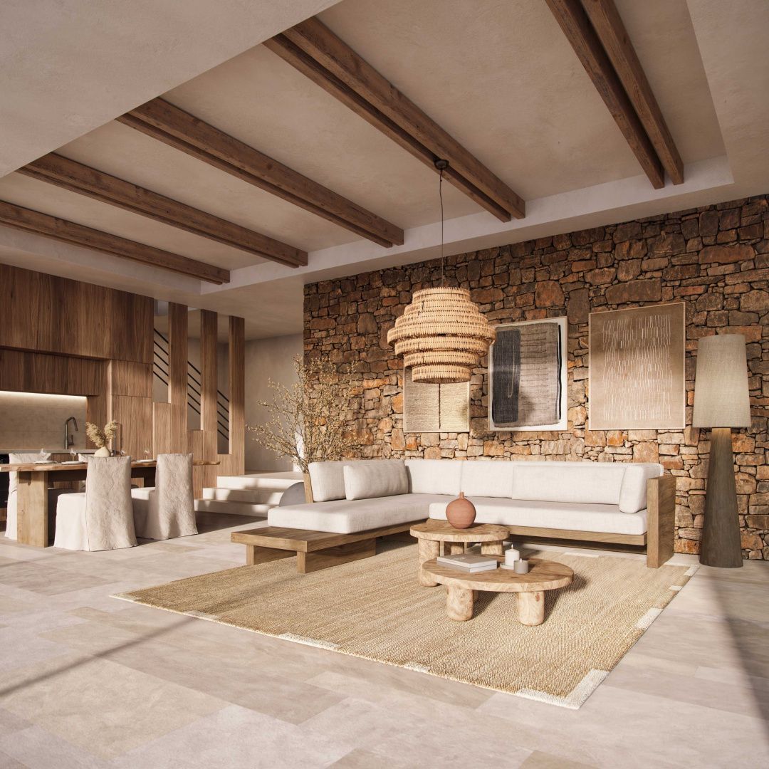 Wohnbereich mit Natursteinwand, beigefarbener Eckcouch, Teppich und Esstisch im Hintergrund.