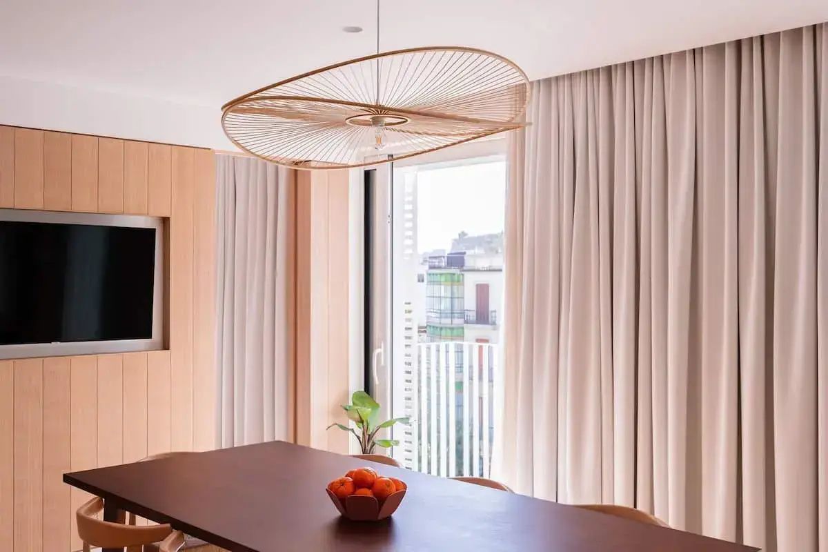 Esstisch aus Holz mit einer großen Lampe und Blick durch das Fenster auf die Stadt.