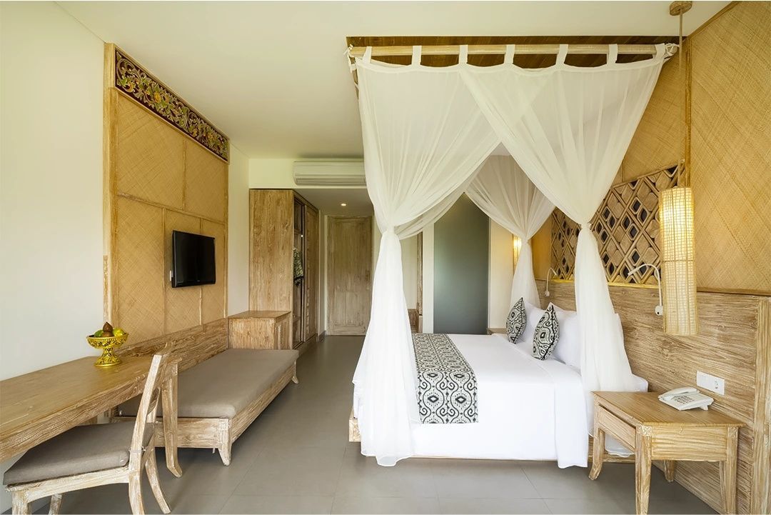 Geräumiges Hotelzimmer mit weißem Himmelbett, Holzschreibtisch und Flachbildfernseher.