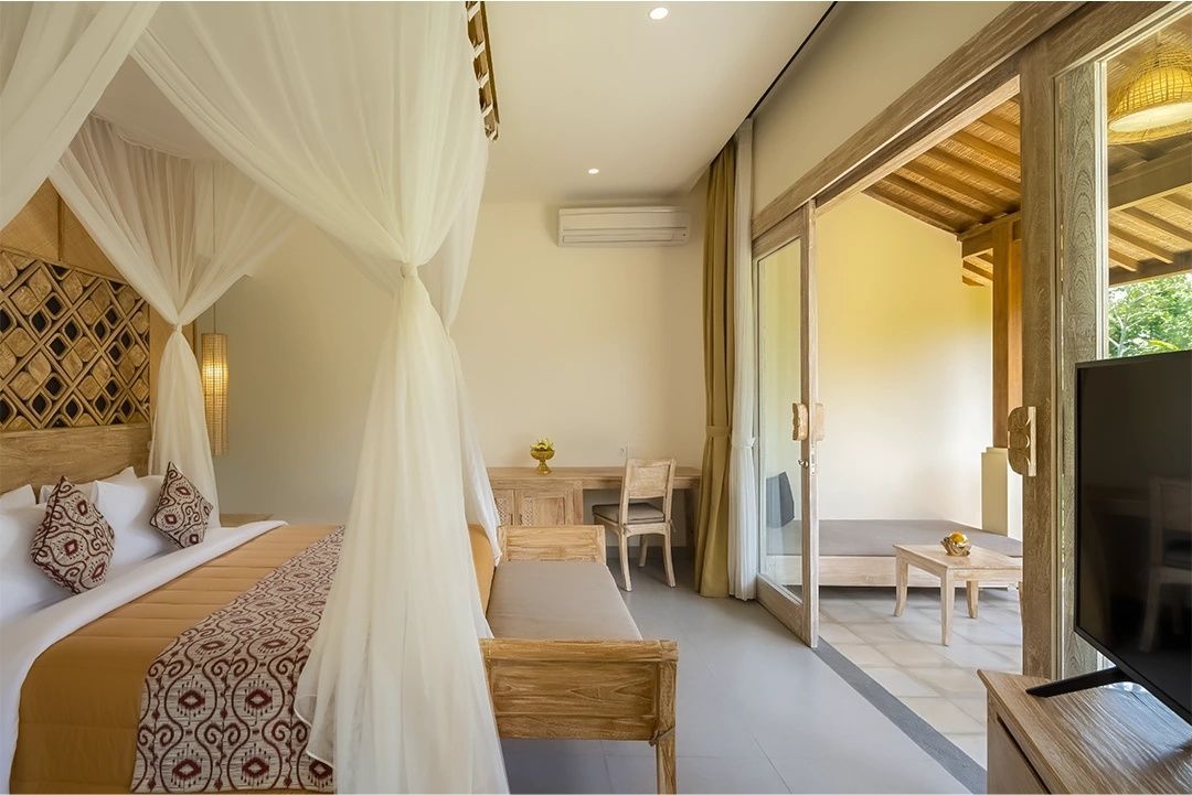 Schlafzimmer mit einem Himmelbett, Holzmöbeln und einer Schiebetür zur Terrasse.