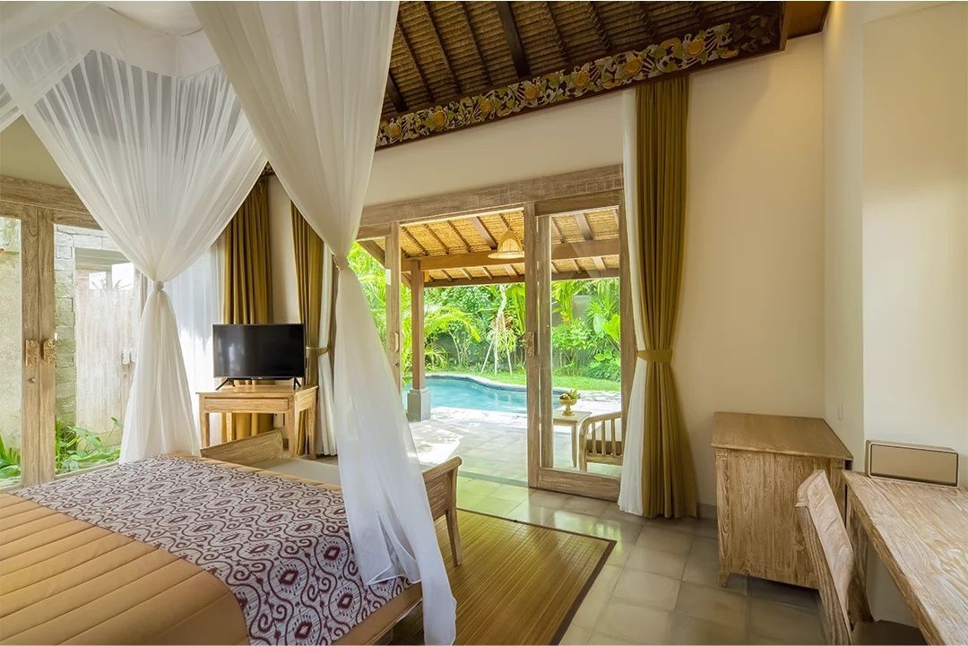 Schlafzimmer mit Himmelbett und geöffneter Tür zum privaten Poolbereich im Garten