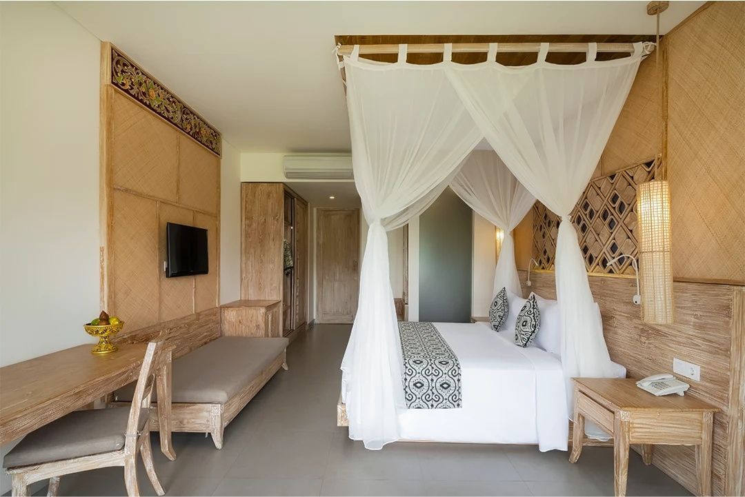 Helles Hotelzimmer mit einem Baldachinbett und Möbeln aus Holz.