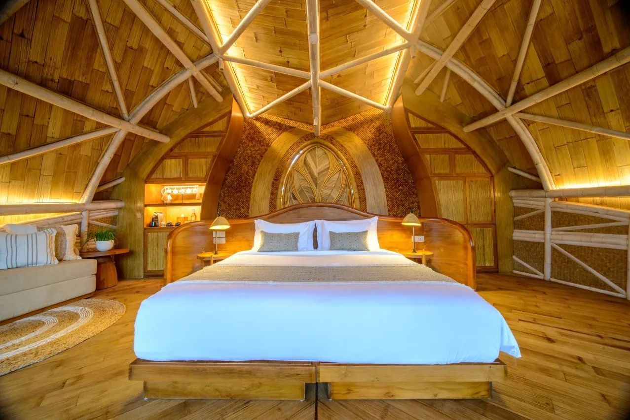 Doppelbett aus Holz unter einer gewölbten Bambusdecke mit warmer Beleuchtung.