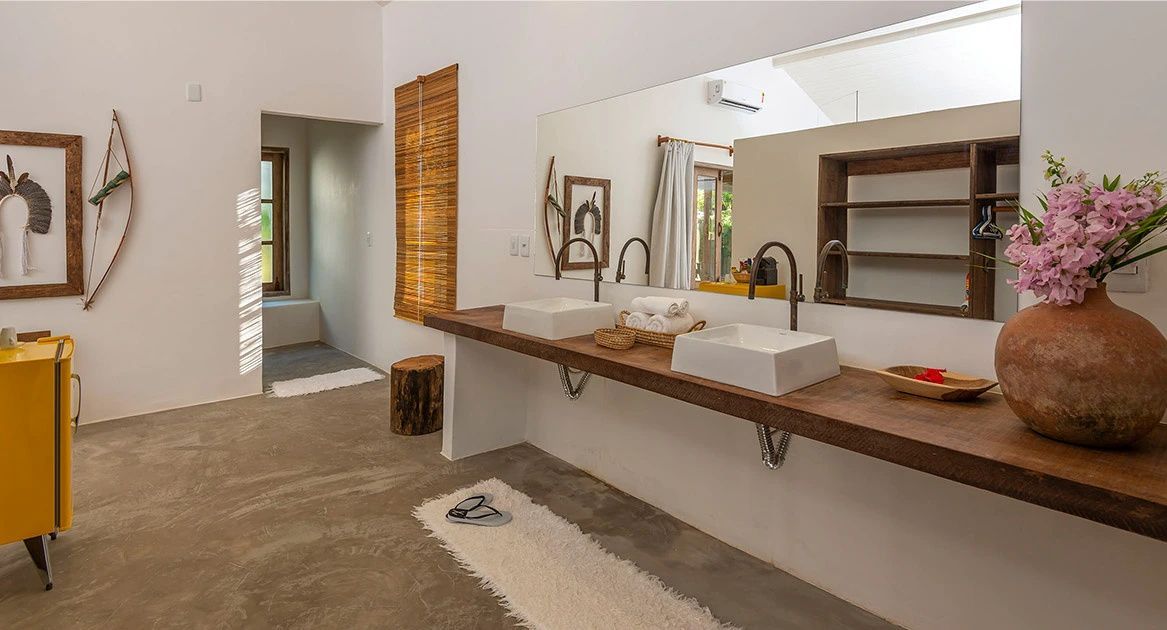 Badezimmer mit doppeltem Waschtisch auf einer Holzplatte und großem Spiegel.