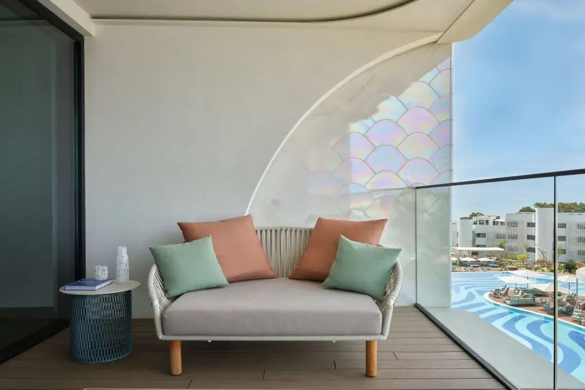 Überdachte Terrasse mit gepolsterter Sitzbank, Kissen und Glasgeländer.
