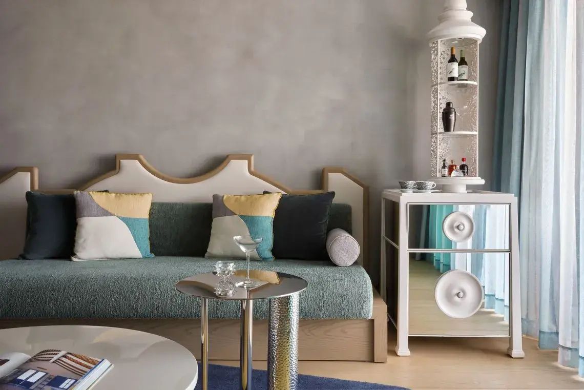 Sitzbereich im Zimmer mit grünem Sofa, kleinem Glastisch und weißem Barregal.
