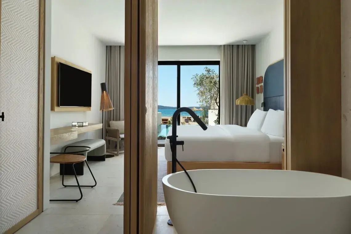 Blick aus dem Badezimmer mit freistehender Badewanne in das Schlafzimmer und zum Außenpool.
