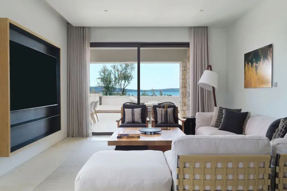 Helles Wohnzimmer mit Sofaecke, Couchtisch und großer Glasfront mit Blick auf das Meer.