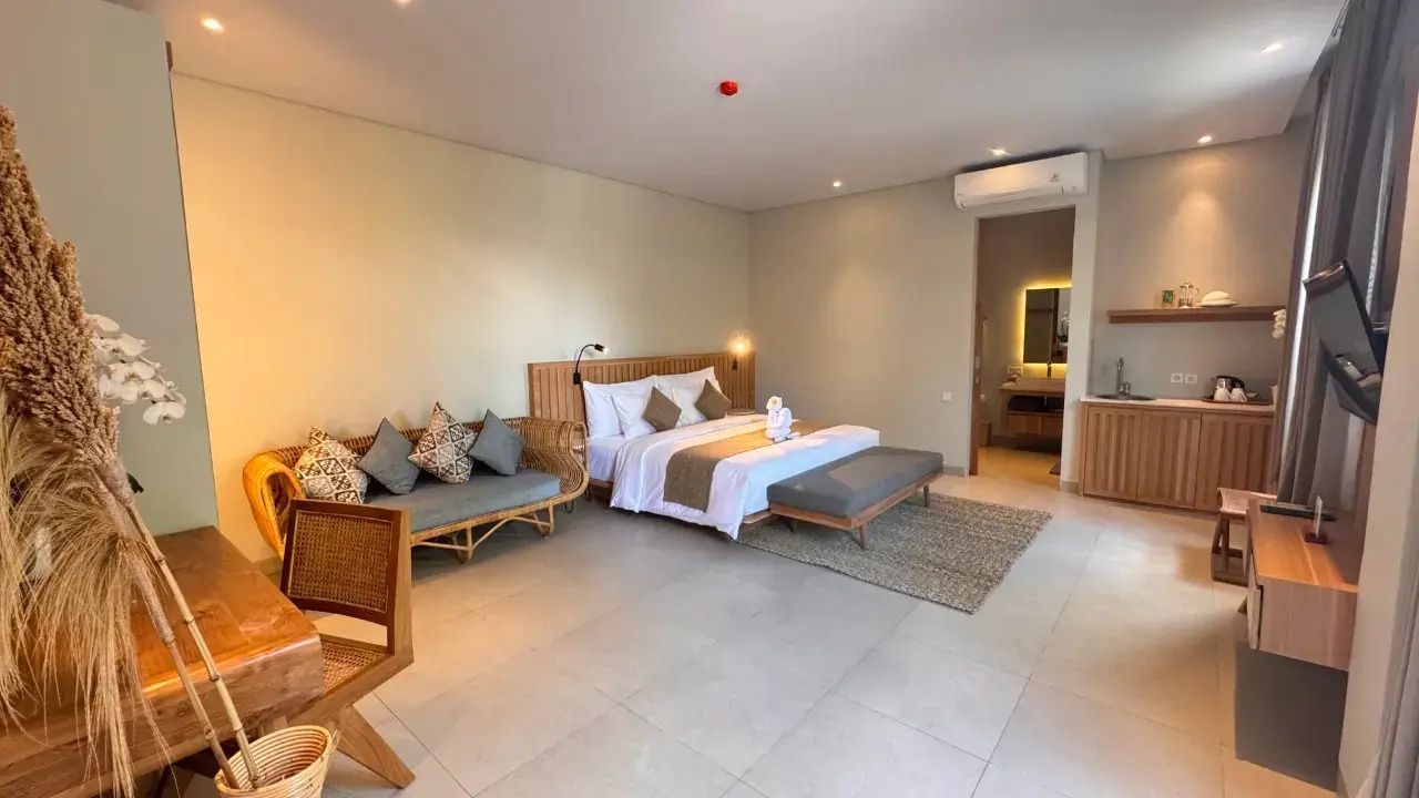 Geräumiges Schlafzimmer mit Holzmöbeln, Sofa und offenem Zugang zum Badezimmer.
