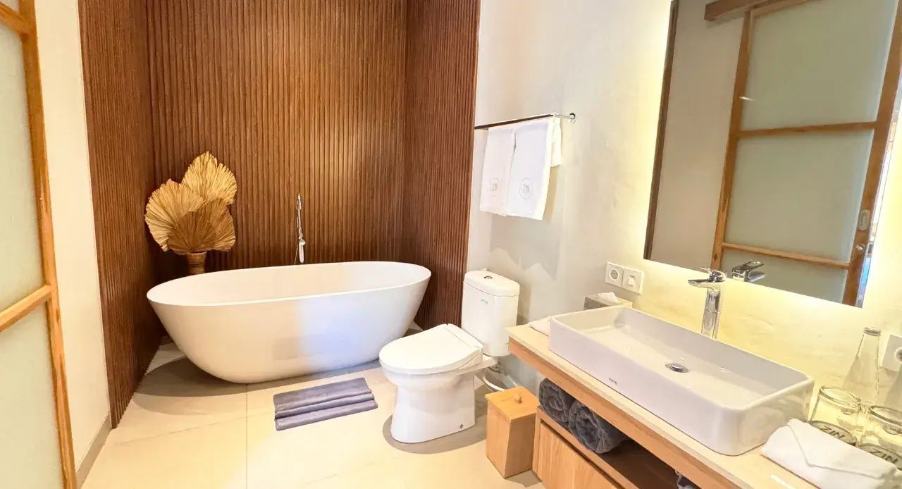 Modernes Badezimmer mit freistehender Badewanne, Toilette und Waschtisch mit Spiegel.
