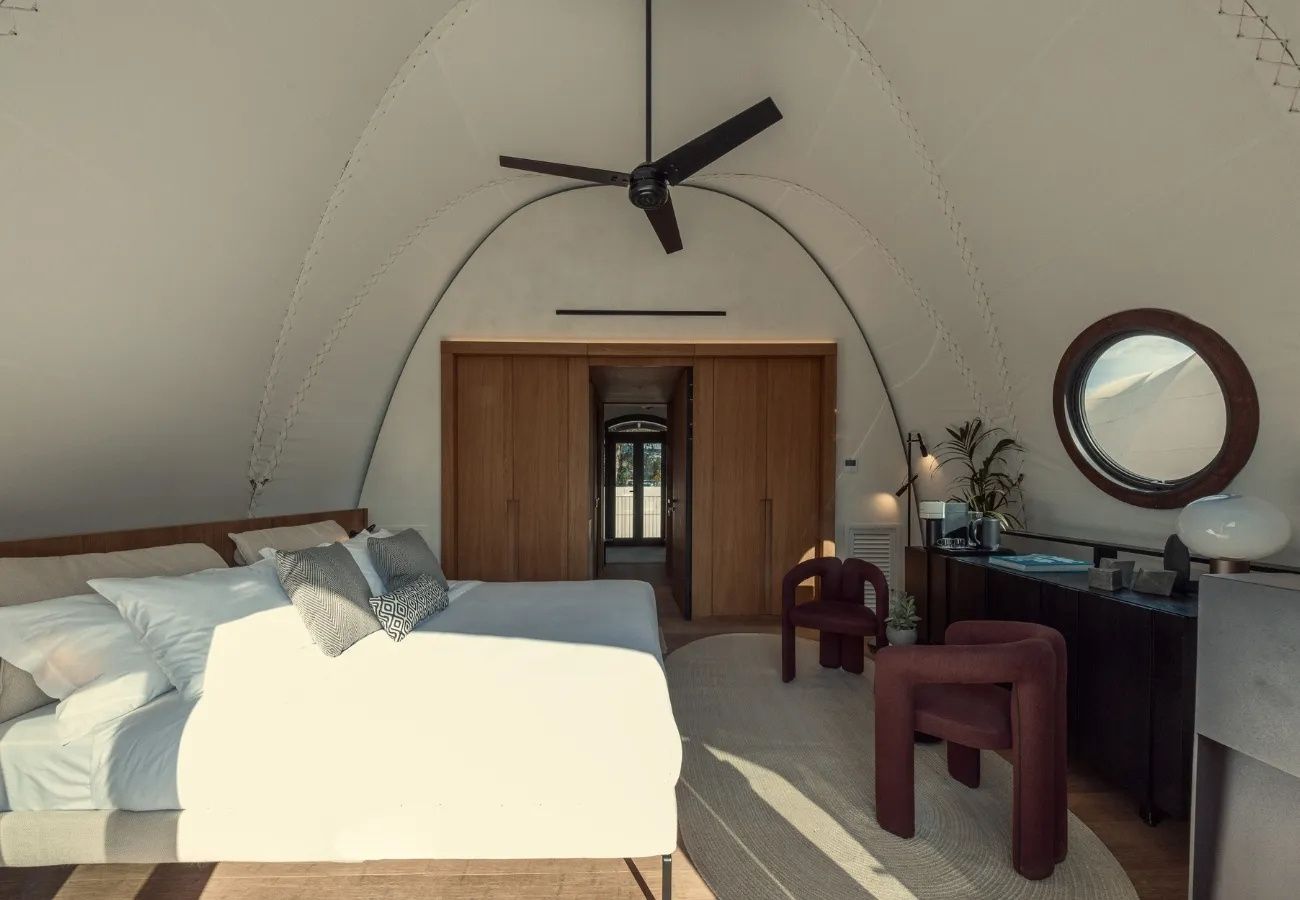 Geräumiges Schlafzimmer unter einer gewölbten Decke mit Doppelbett und Sesseln.
