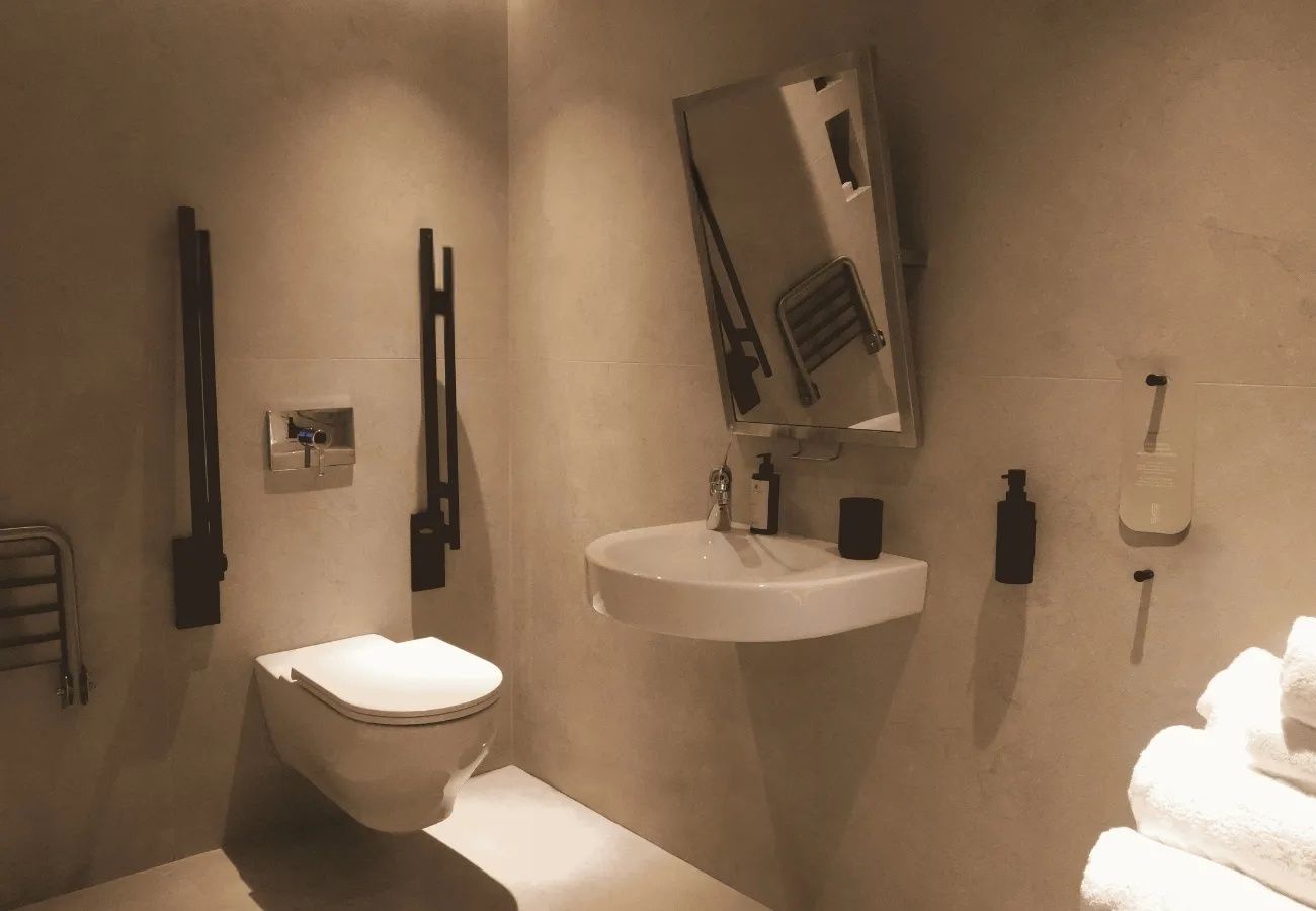 Modernes Badezimmer mit weißem Waschbecken, Spiegel und wandhängender Toilette.