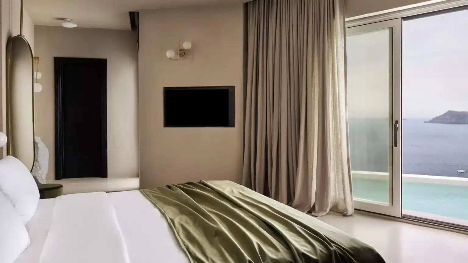 Schlafbereich mit Bett, grünem Bezug, Fernseher an der Wand und beigen Vorhängen.