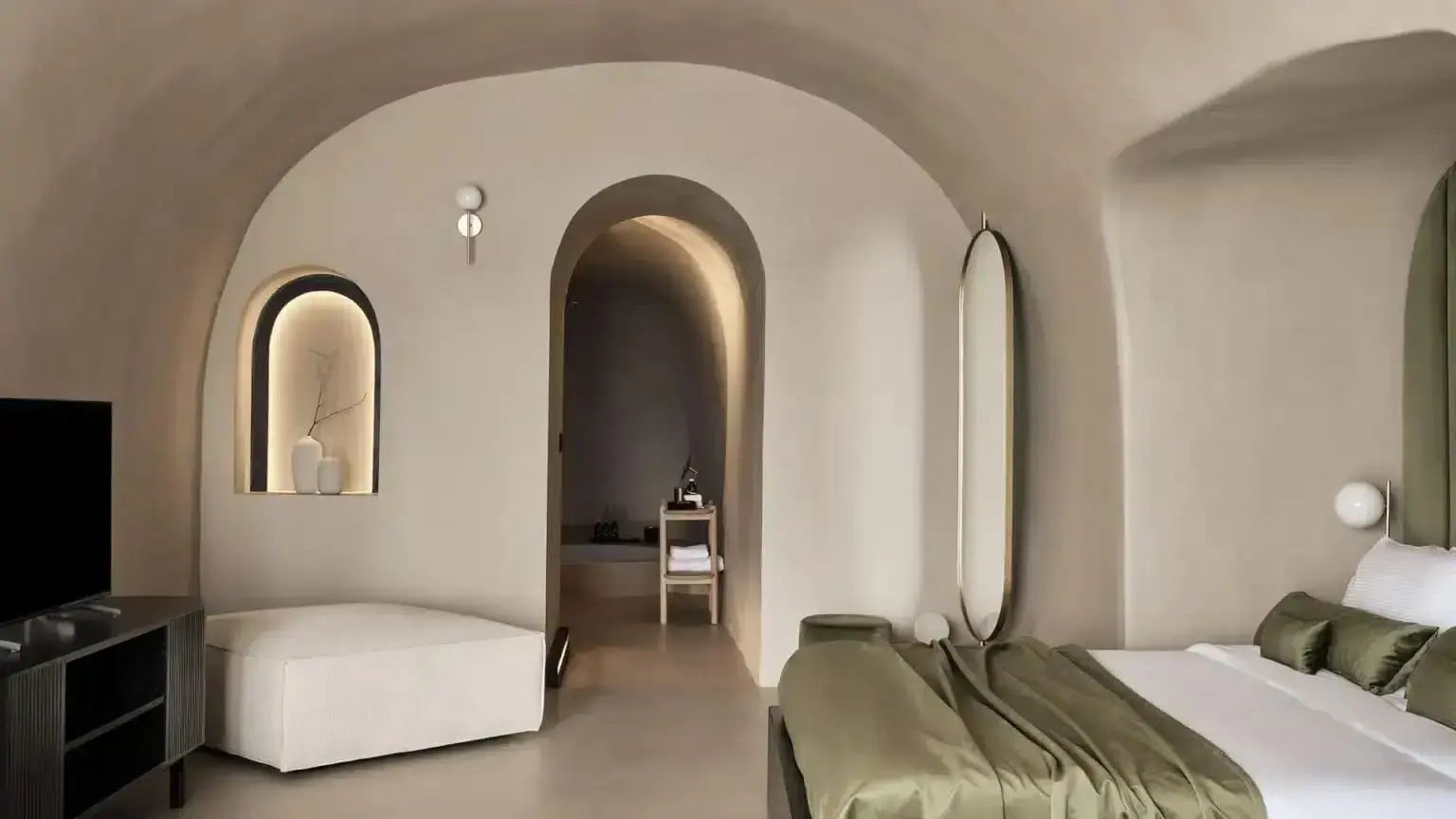 Wohnbereich in Gewölbeform mit Rundbögen, Bett, Spiegel und minimalistischen Möbeln.
