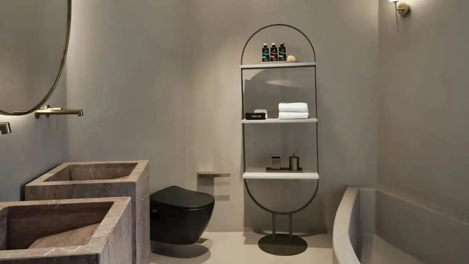Modernes Badezimmer mit schwarzem WC, Steinwaschbecken und einem freistehenden Regal für Pflegeprodukte.