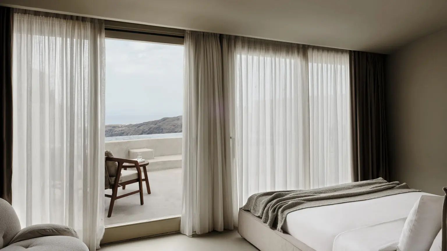 Schlafzimmer mit großen Fenstern und Blick auf eine Terrasse sowie das Meer.