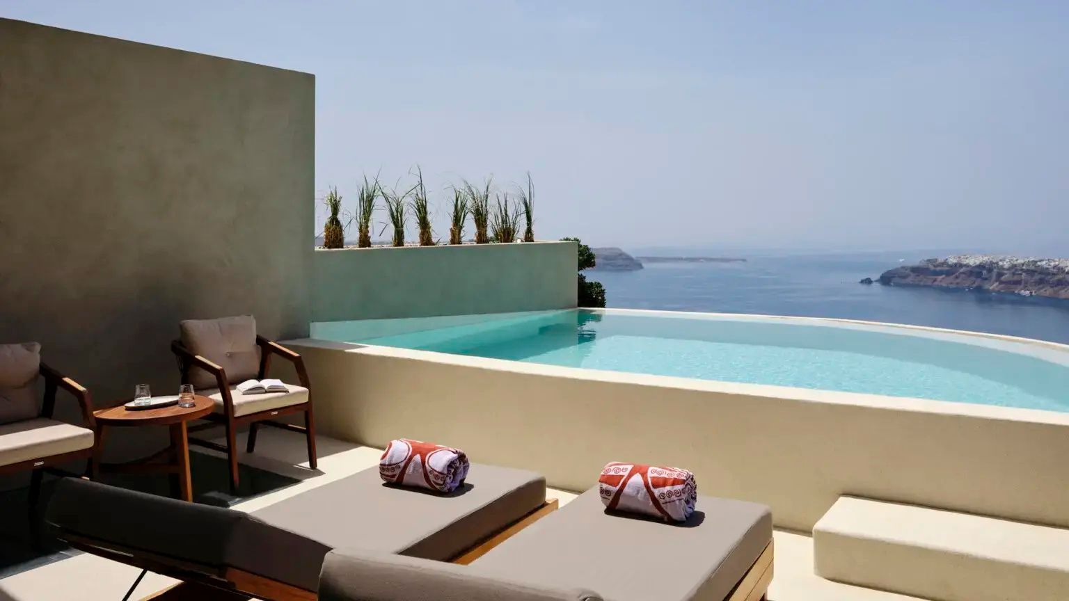 Private Terrasse mit zwei Sonnenliegen, Handtüchern und einem hellblauen Pool.