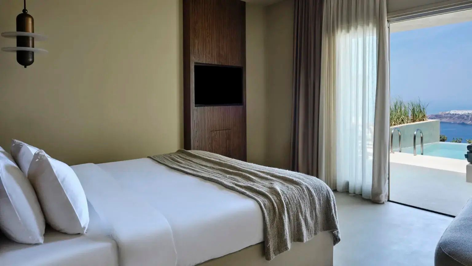 Doppelbett mit weißer Bettwäsche und an der Holzwand montiertem Fernseher im Hotelzimmer.