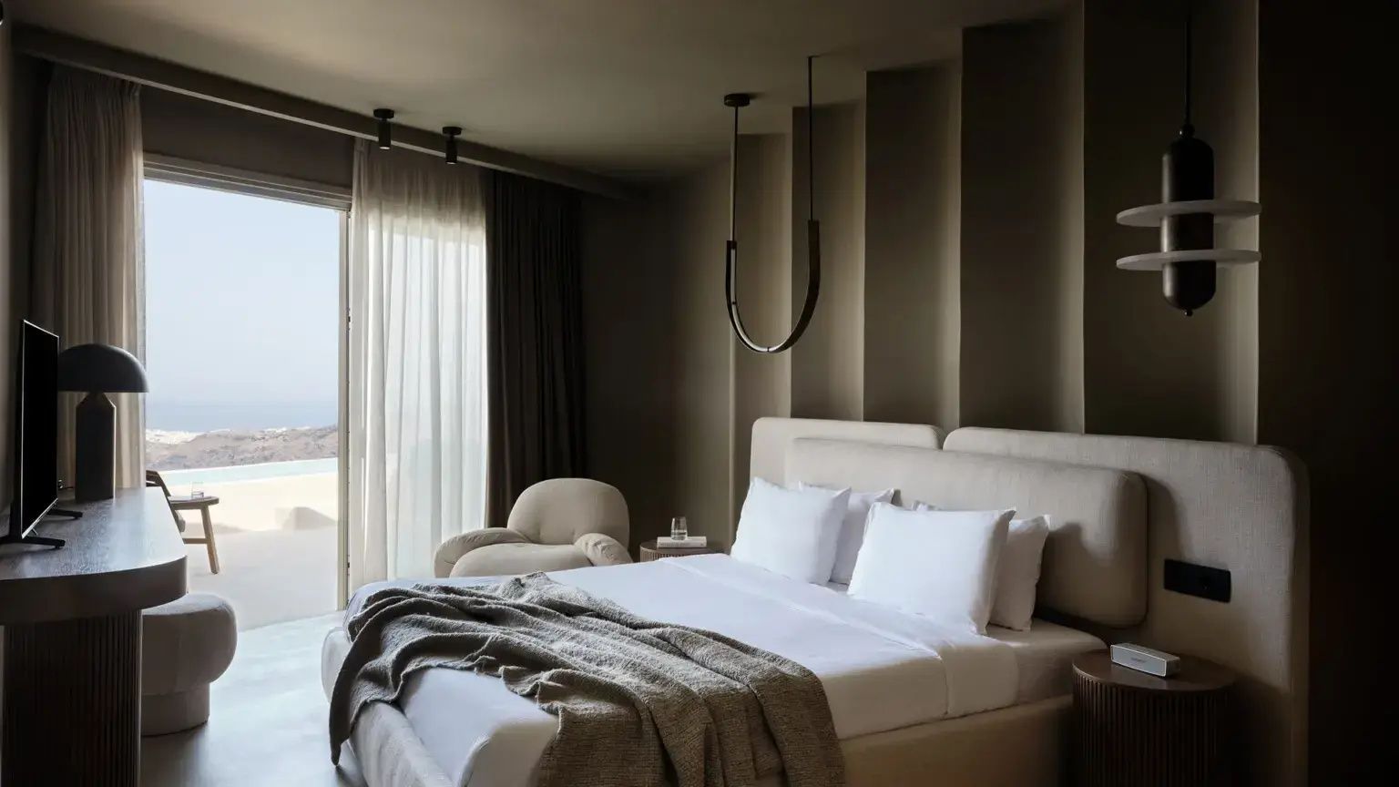 Modern eingerichtetes Schlafzimmer mit Doppelbett, Sessel und hellem Vorhang am Fenster.