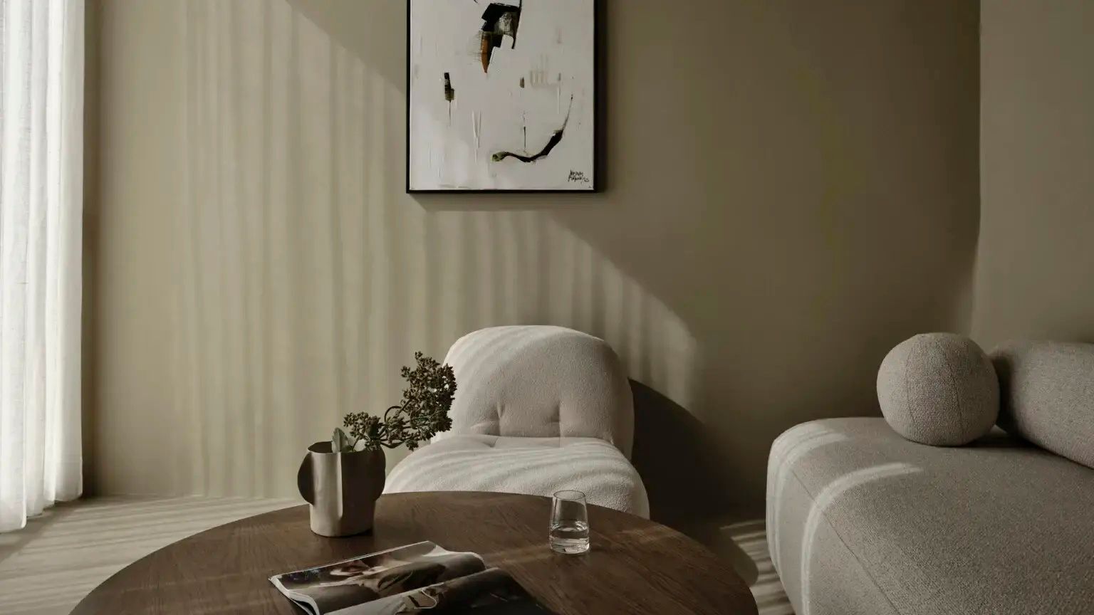 Heller Wohnbereich mit beigem Sessel, rundem Holztisch und abstraktem Bild an der Wand.