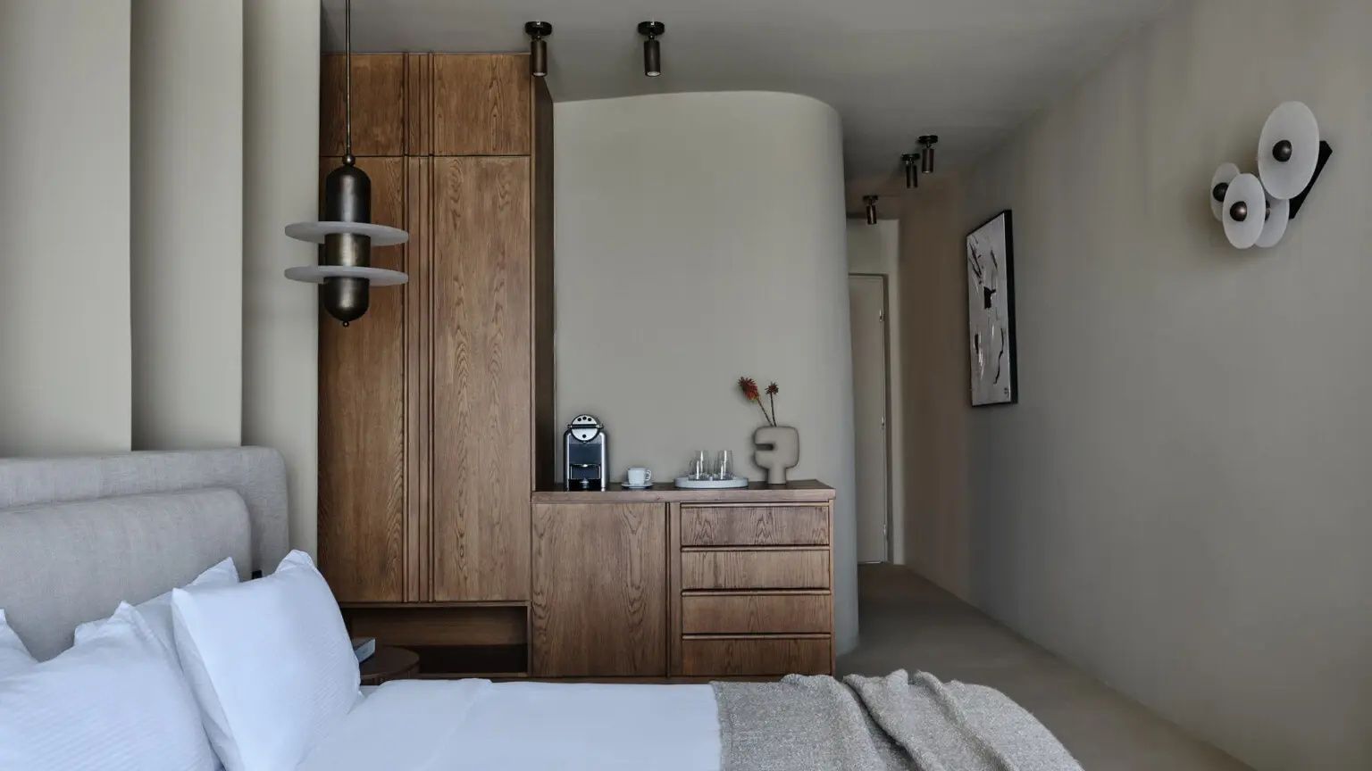 Heller Raum mit einem Holzschrank, einer Kommode mit Kaffeemaschine und flurartigem Zugang.