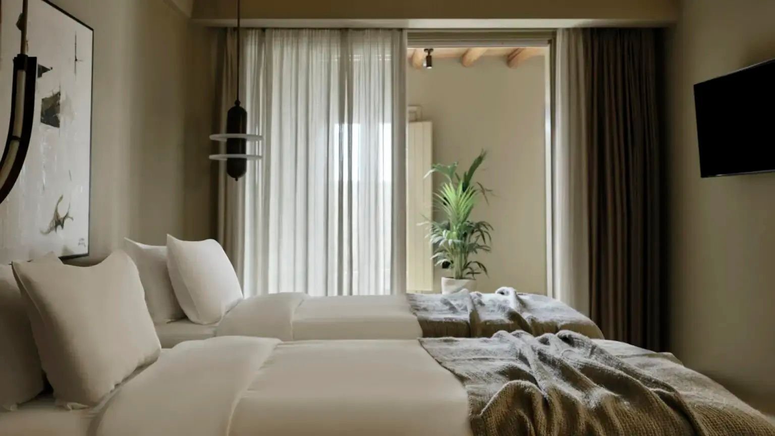 Modernes Schlafzimmer mit zwei Betten, hellem Vorhang und Zimmerpflanze im Hintergrund.