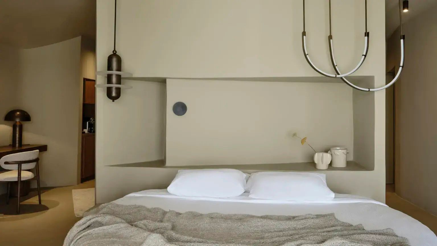 Doppelbett mit weißen Kissen und beigefarbener Tagesdecke in hell gestaltetem Schlafzimmer