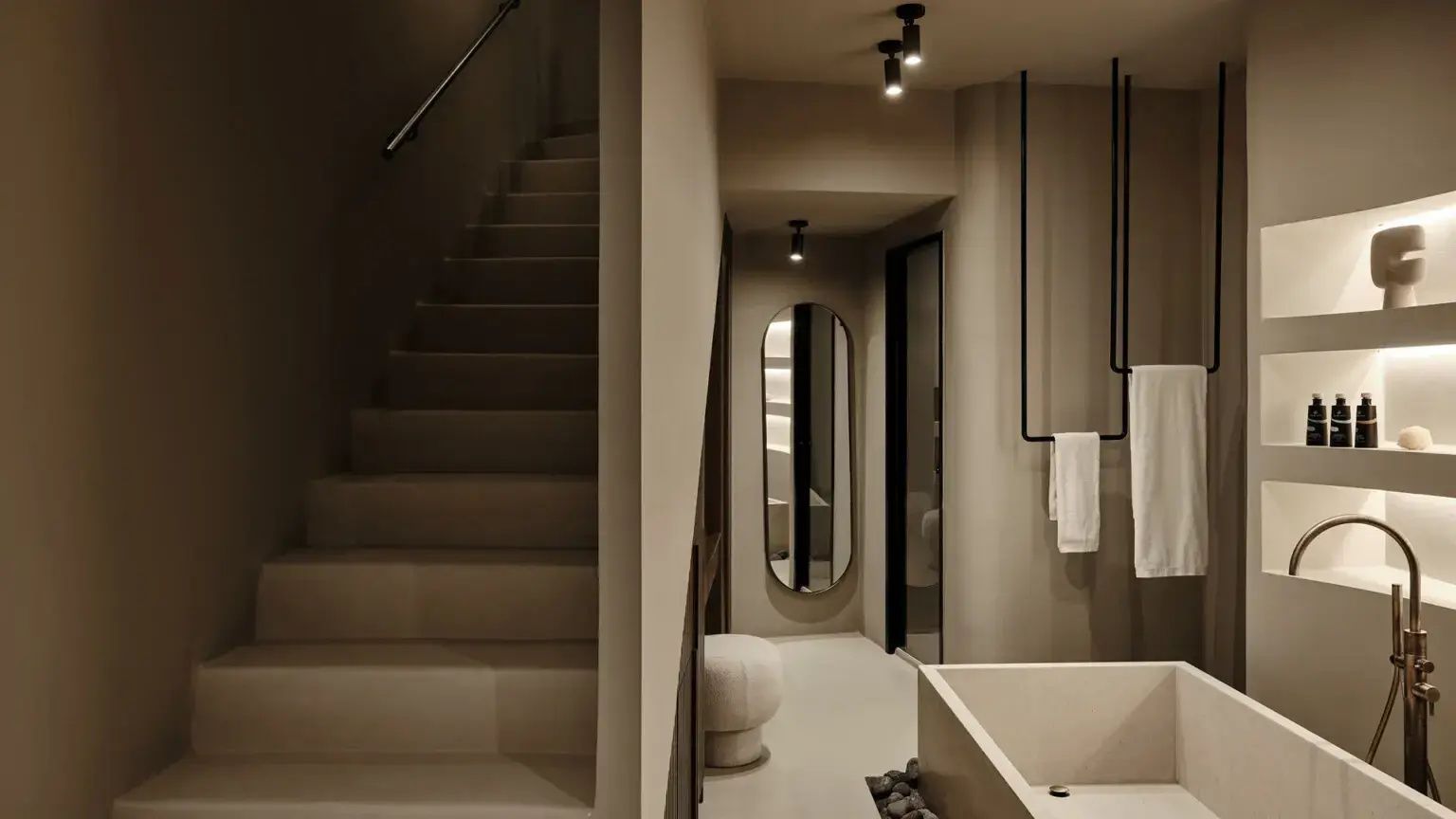 Treppenaufgang im modernen Hotelzimmer mit ovalem Wandspiegel und Natursteindekor.