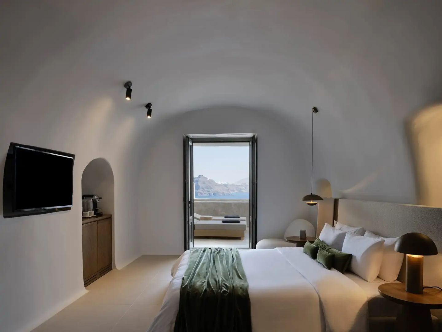 Weiß gewölbtes Schlafzimmer mit Doppelbett und Blick durch die offene Tür auf das Meer.