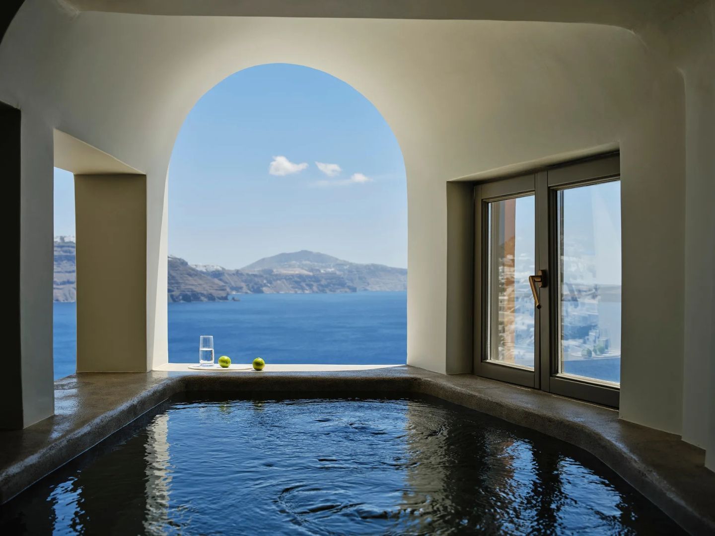 Innenpool in einer Felsengrotte mit großem Rundbogen und freiem Blick auf das blaue Meer.
