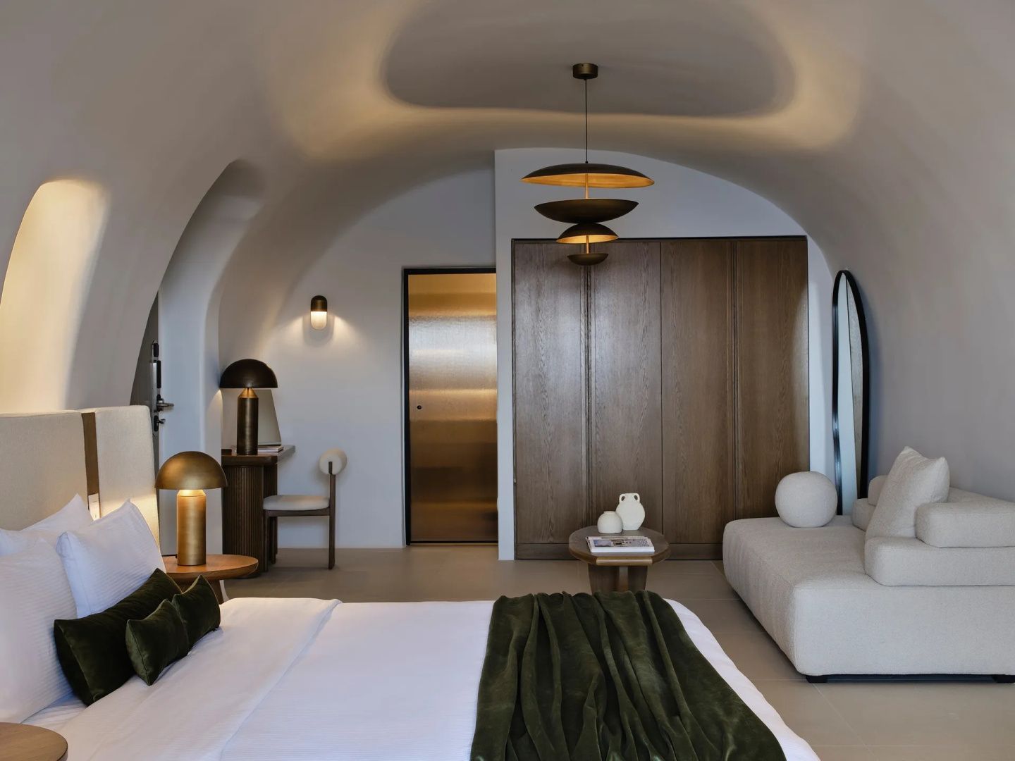 Schlafbereich mit weißem Sofa, Holzschrank und Blick auf die gewölbte Decke.