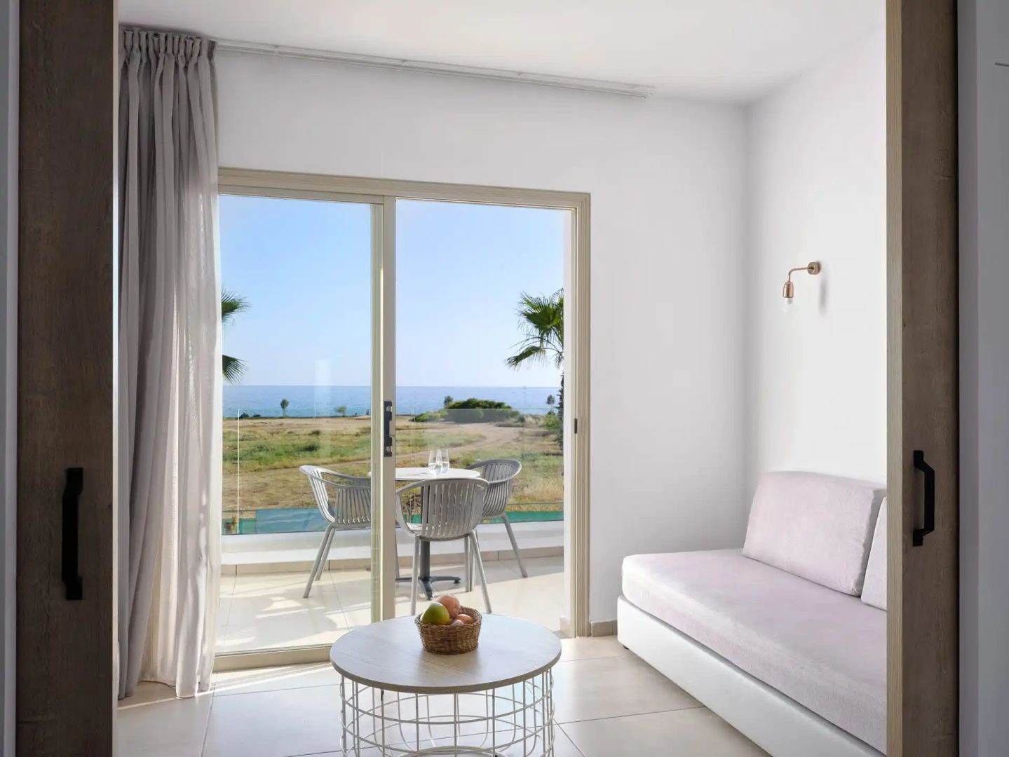 Wohnbereich mit Schlafsofa und Panoramablick durch die Balkontür auf das Meer.