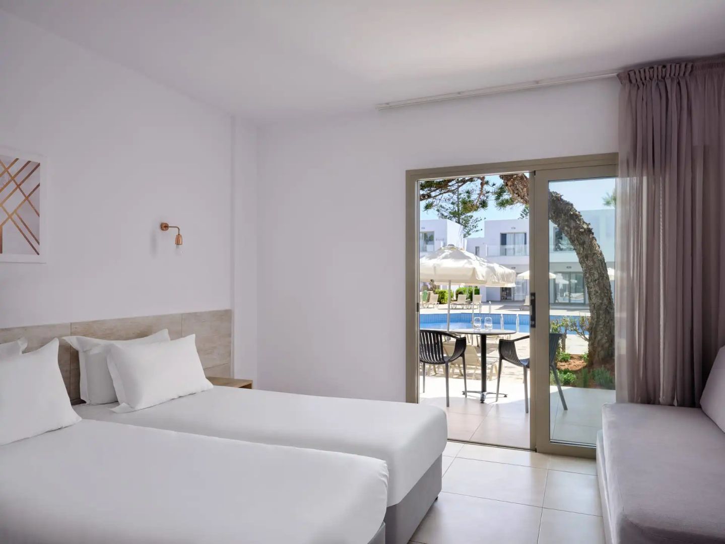 Helles Hotelzimmer mit zwei Einzelbetten und Terrassentür mit Blick zum Poolbereich.