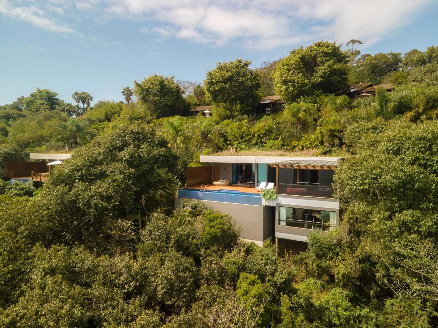 Moderne Hotelvilla an einem bewaldeten Hang mit eigenem Pool auf der Terrasse.