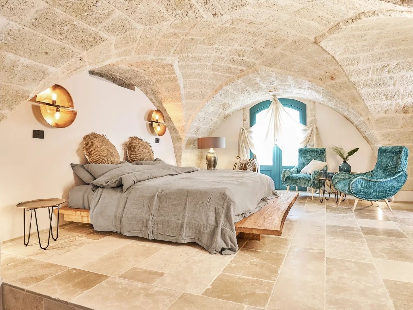 Schlafzimmer unter einem Gewölbe aus Naturstein mit Holzbett und Sitzecke.