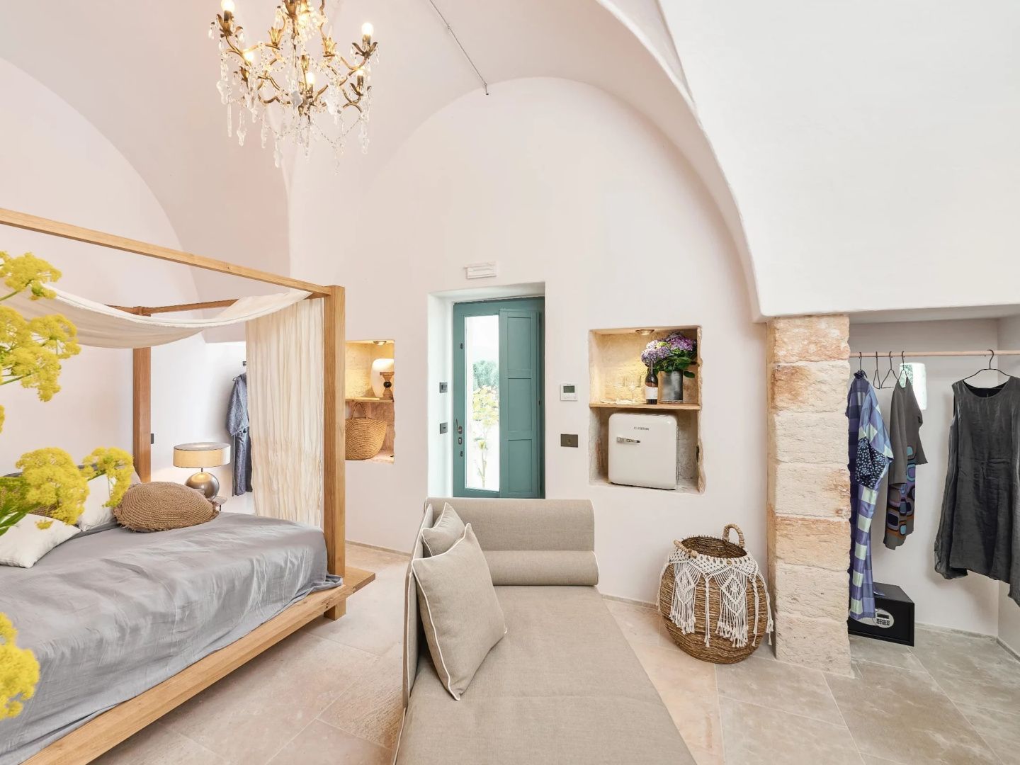 Geräumiges Zimmer mit Gewölbedecke, Himmelbett aus Holz, Tagesbett und grüner Eingangstür.