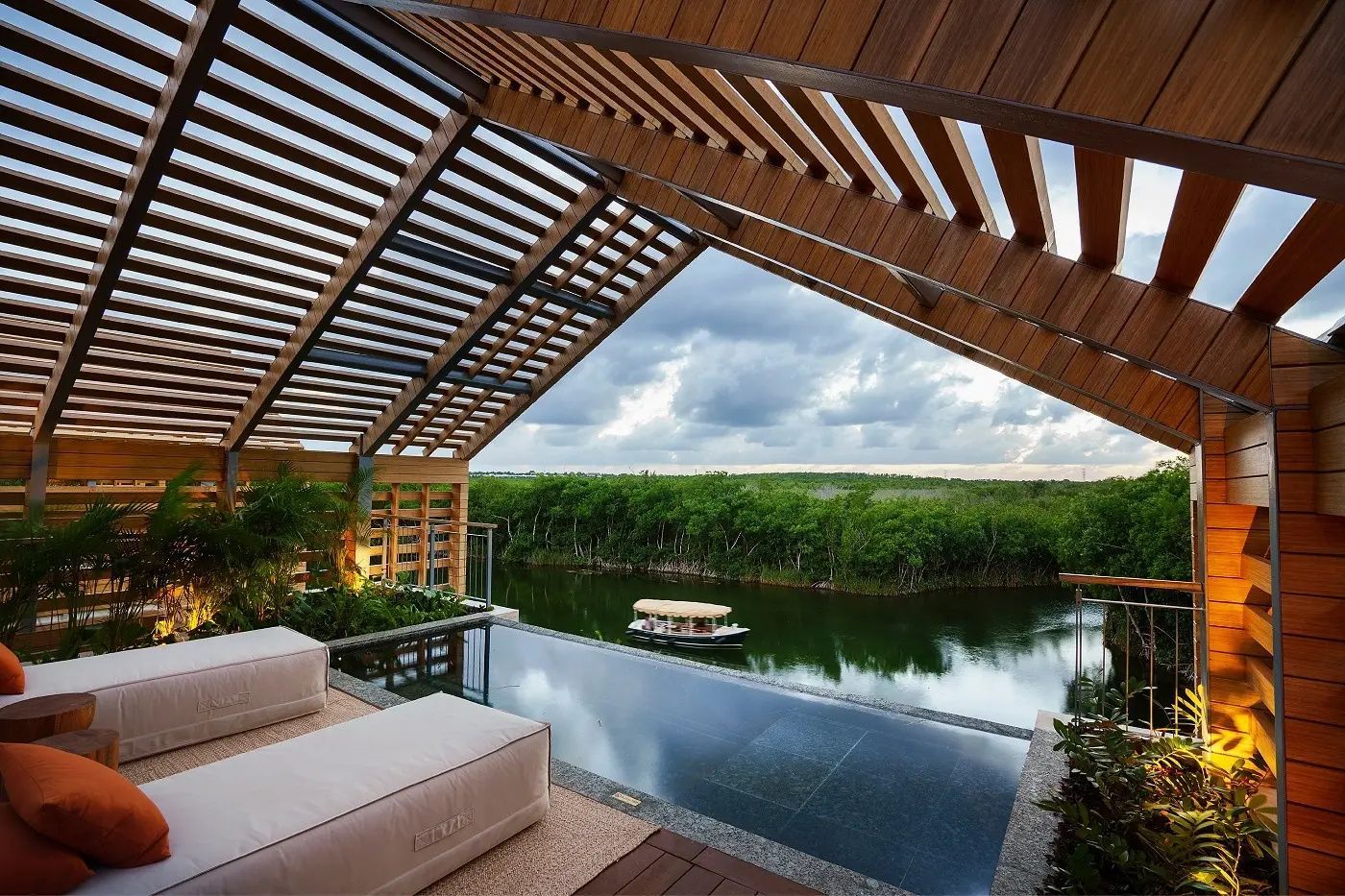 Terrasse mit privatem Pool und Holzüberdachung mit Blick auf eine grün bewachsene Lagune.