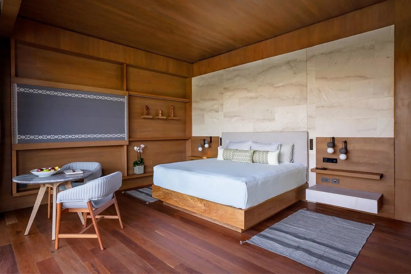 Modernes Schlafzimmer mit Holzverkleidung, großem Doppelbett und heller Steinwand.