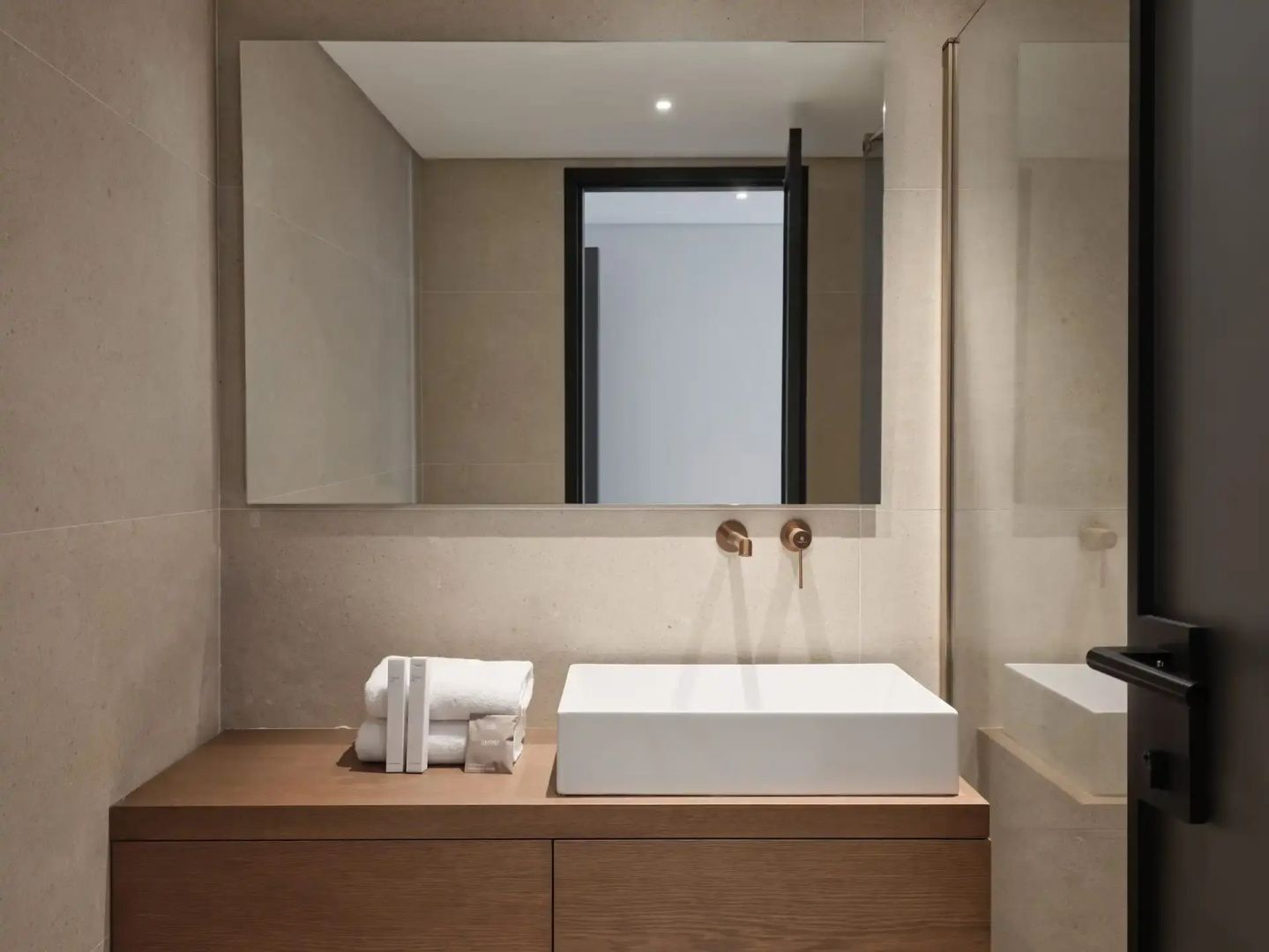 Modernes Badezimmer mit einem rechteckigen Waschbecken, großem Spiegel und Holzwaschtisch.