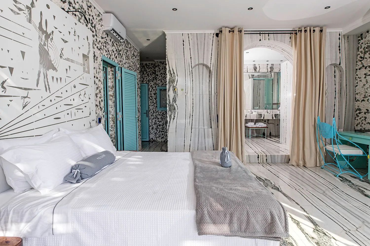 Schlafzimmer mit Blick auf den angrenzenden Badezimmerbereich mit Waschtisch.
